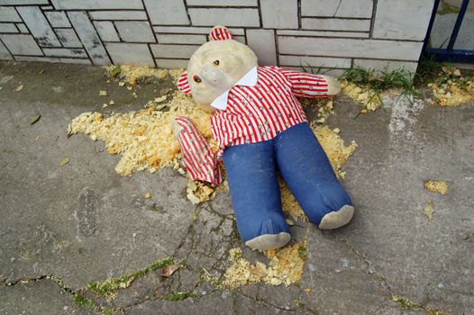 Torn teddy bear on the sidewalk. �oy resembling crime victim in murder scene.