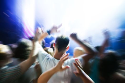People with hands up having fun on a music concert / disco party. Dynamic motion.
