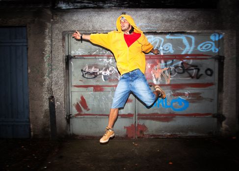 Young man jumping / dancing on grunge graffiti wall background