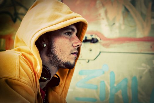 Young man profile portrait in hooded sweatshirt / jumper on grunge graffiti wall