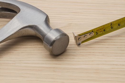 Old hammer and tape measure on wood background 