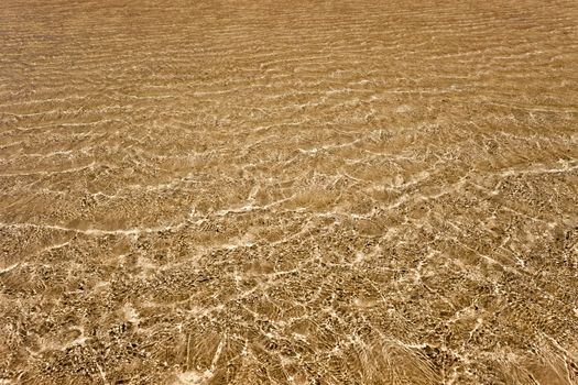 Transparent water above the golden sand