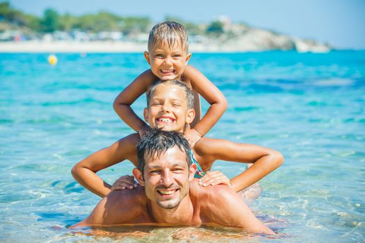 Family - father with his kids have fun and swimming in the transparent sea