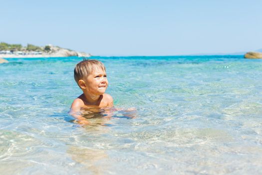 Cute boy playing and swimming in the transparent sea