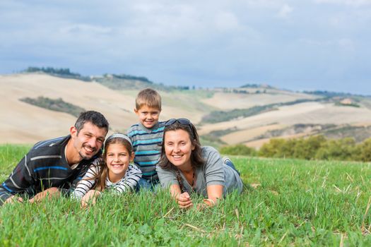 Happy family having fun on vacations in Tuscan against cypress alley background