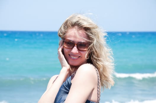 Smiling young woman in sunglasses posing on sea coast