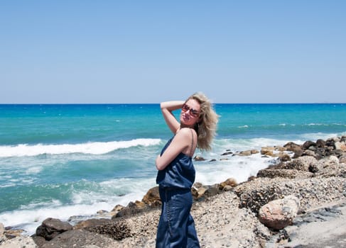 Young woman in sunglasses posing on sea coast