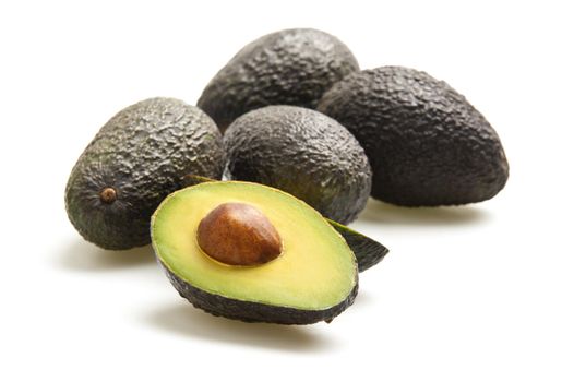Avocados, one cut in half, photographed on a white background.