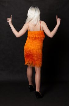 Full length portrait of drag queen, view from the back. Man dressed as Woman, on black background