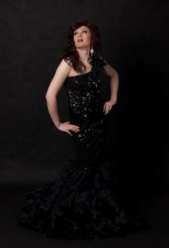 Full length portrait of drag queen. Man dressed as Woman, on black background