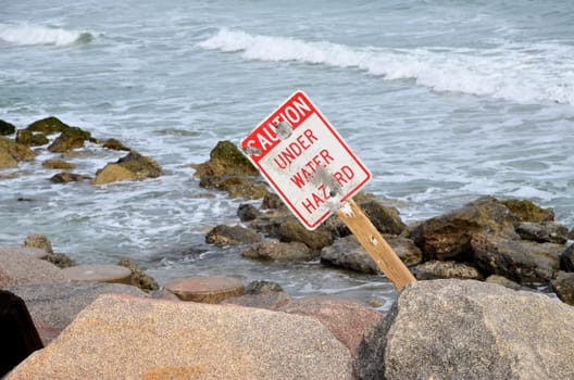 A caution sign along the rocky shore in North Carolina