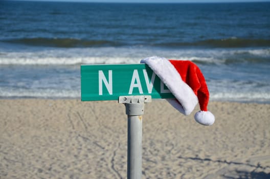 A santa hat on a street sign at the ocean during the fall.