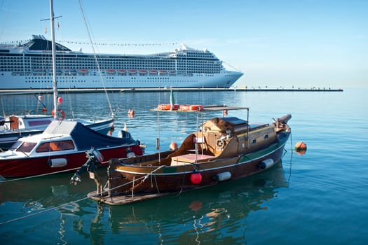 Big white cruise liner in harbor with boats on a foreground