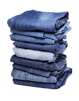 A Stack of different shades of blue denim jeans isolated on white with natural shadow.