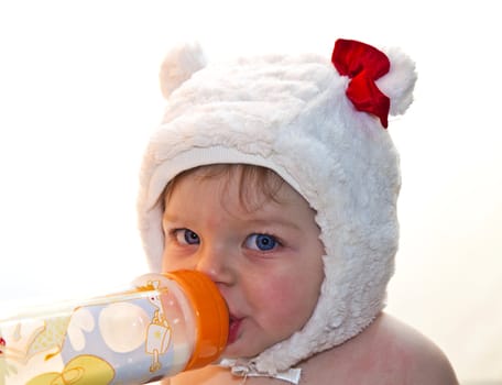 Pretty baby girl drinking milk from bottle 