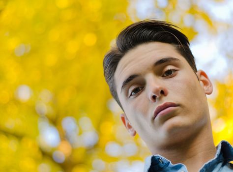 Attractive young male model with autumn leaves behind