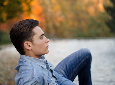 Good looking young man outdoors in nature (river, lake, trees)