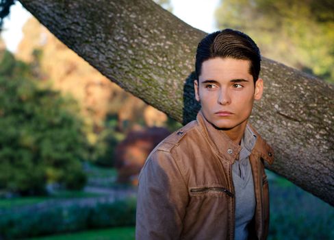 Handosome young guy in fall (autumn) outdoors in nature, at dusk