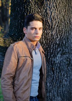 Portrait of handsome young man with leather jacket and tree