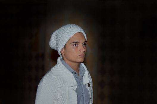 Handsome young male model on dark background, with wool hat