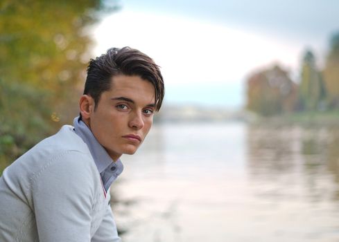 Good looking young man outdoors in nature (river, lake, trees)