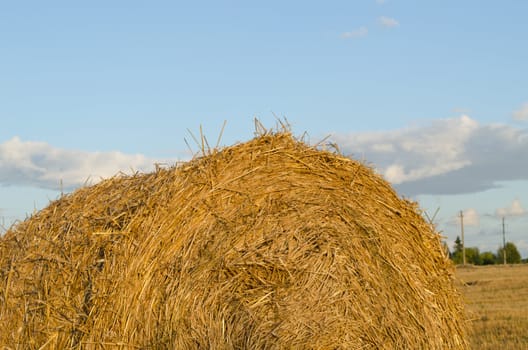 Closeup of straw bales on background of blue cloudy sky in autumn