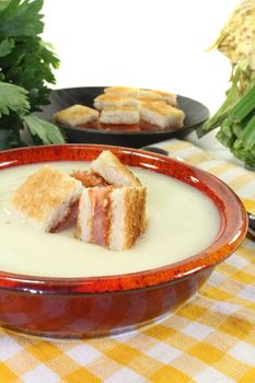 cooked Cream of celery soup with salmon croutons on a checkered napkin before bright background