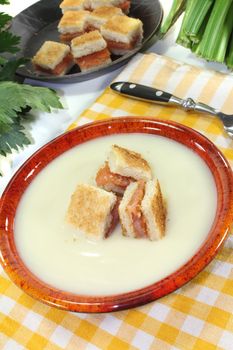 freshly cooked Cream of celery soup with salmon croutons on a checkered napkin before light background