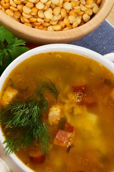 Pea Soup with Potato and Smoked Ham in Bowl closeup on Yelow Peas Bowl background