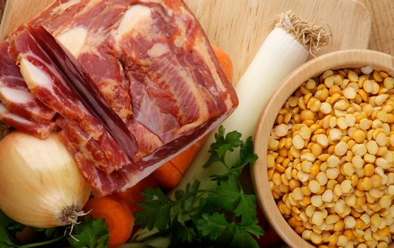 Ingredients of Pea Soup with Yellow Pea, Onion, Leek, Carrot, Parsley and Smoked Ham on Wooden Cutting Board closeup