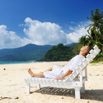 Man in white relaxing on a tropical beach