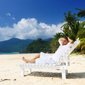 Man in white relaxing on a tropical beach