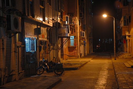 Empty street and tenement house by night in Chinese city. 