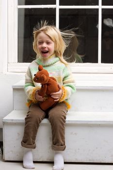  little girl with a toy in the hands with flowing hair from the fan