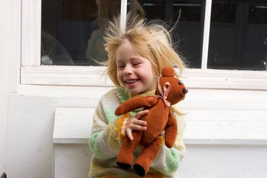  little girl with a toy in the hands with flowing hair from the fan