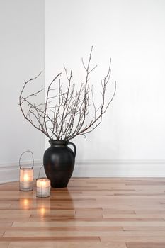 Cozy lanterns and tree branches in a vase, decorating a room.