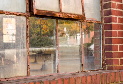 Detail of rusting window frame in brick warehouse or factory reflecting fall colors