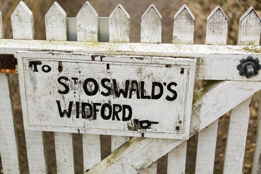 White painted sign to footpath to ancient church of St Oswald in Widford Oxford