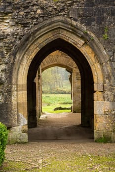 Entrance arches of Minster Lovell in Cotswold village with graveyard