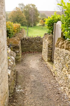 Narrow footpath between stone walls from Swinbrook to Widford in Windrush Valley