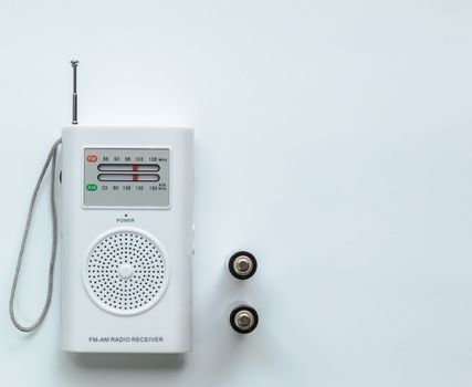 Small white radio receiver with two batteries. white background