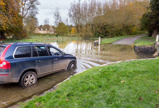 Car crossing through a deep river at road ford on Shill Brook at Shilton Oxfordshire