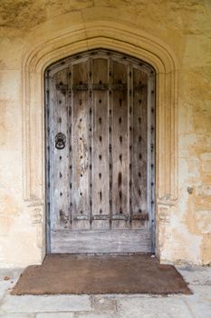 Old oak wood and stud door in cotswold stone entrance archway