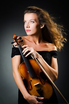 Woman with violin in dark room