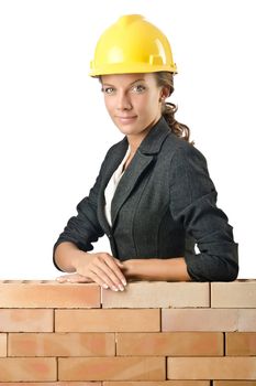 Young female builder near brick wall