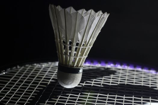 side-lit tennis racket hitting shuttlecock in the tip