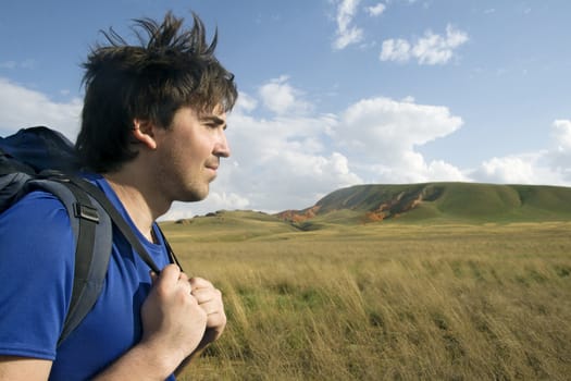 Profile of a young backpacker with green valley in the background