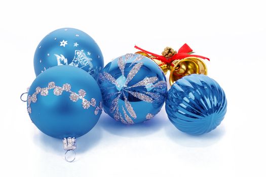 Blue christmas balls and small golden bells on white