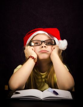 Sad girl who thinks what to write to Santa Claus