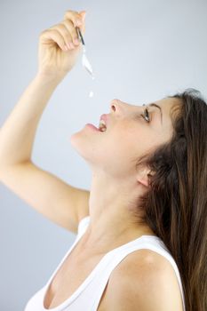 Beautiful female model eating one drop of yogurt with spoon 